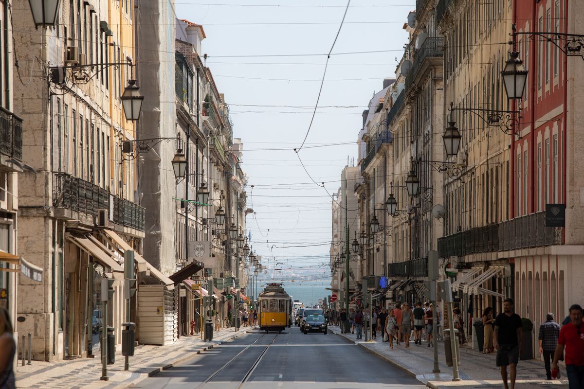 A yellow tram on a historic street in Lisbon, Portugal